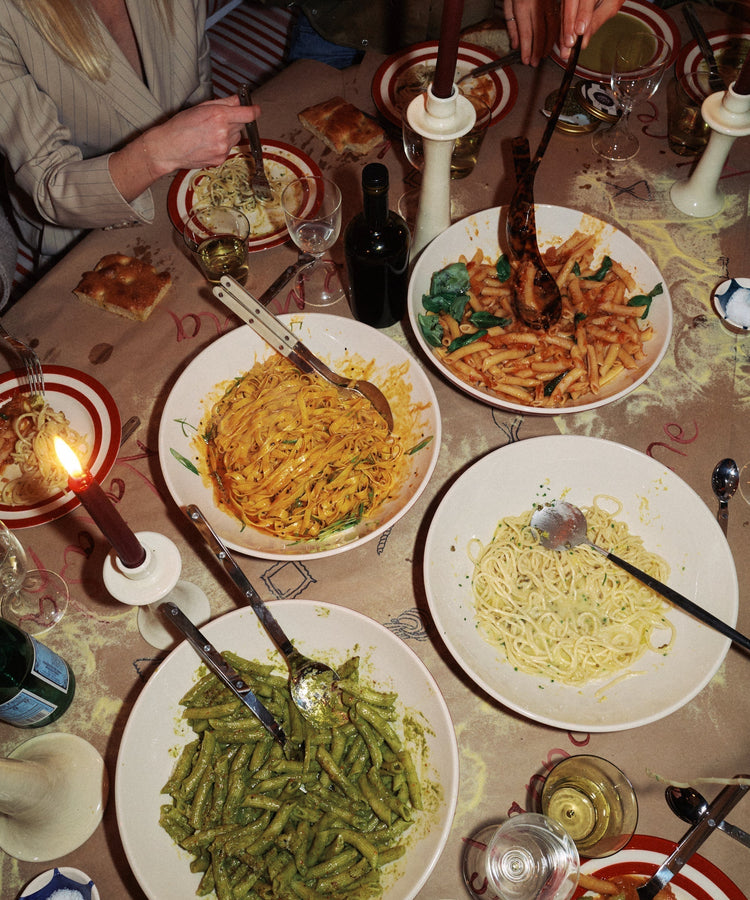 table with bowls of pasta and hands