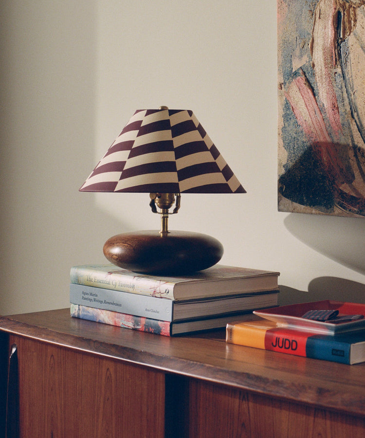 Striped table lamp on books and a wooden sideboard