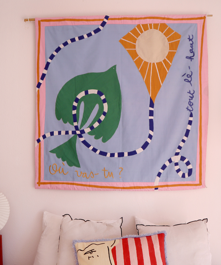 quilt in purple and pink hues on pink wall