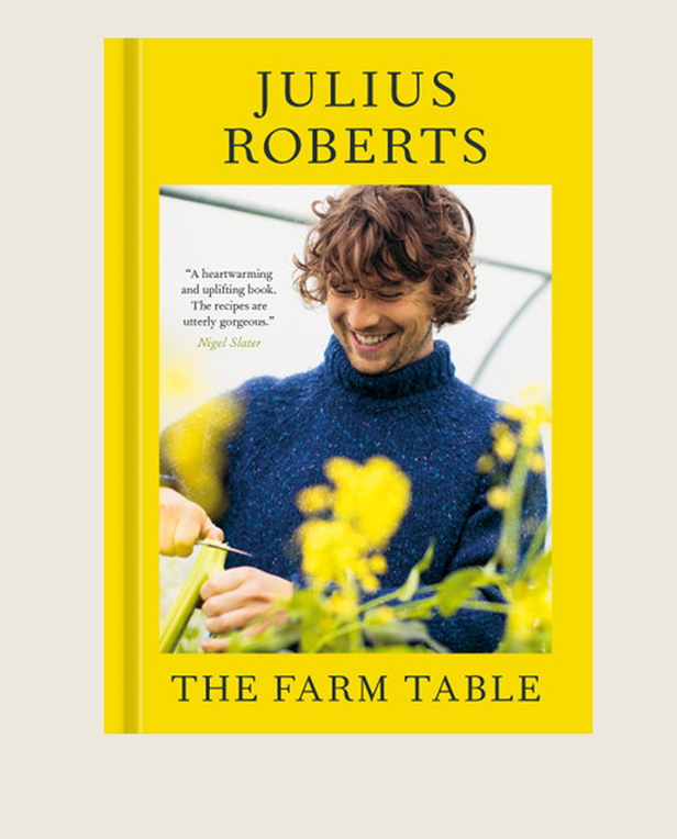 Book cover of 'The Farm Table' by Julius Roberts with a man in a blue sweater holding plants.