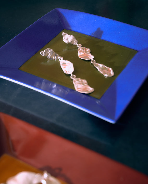 silver earings on blue and green square tray