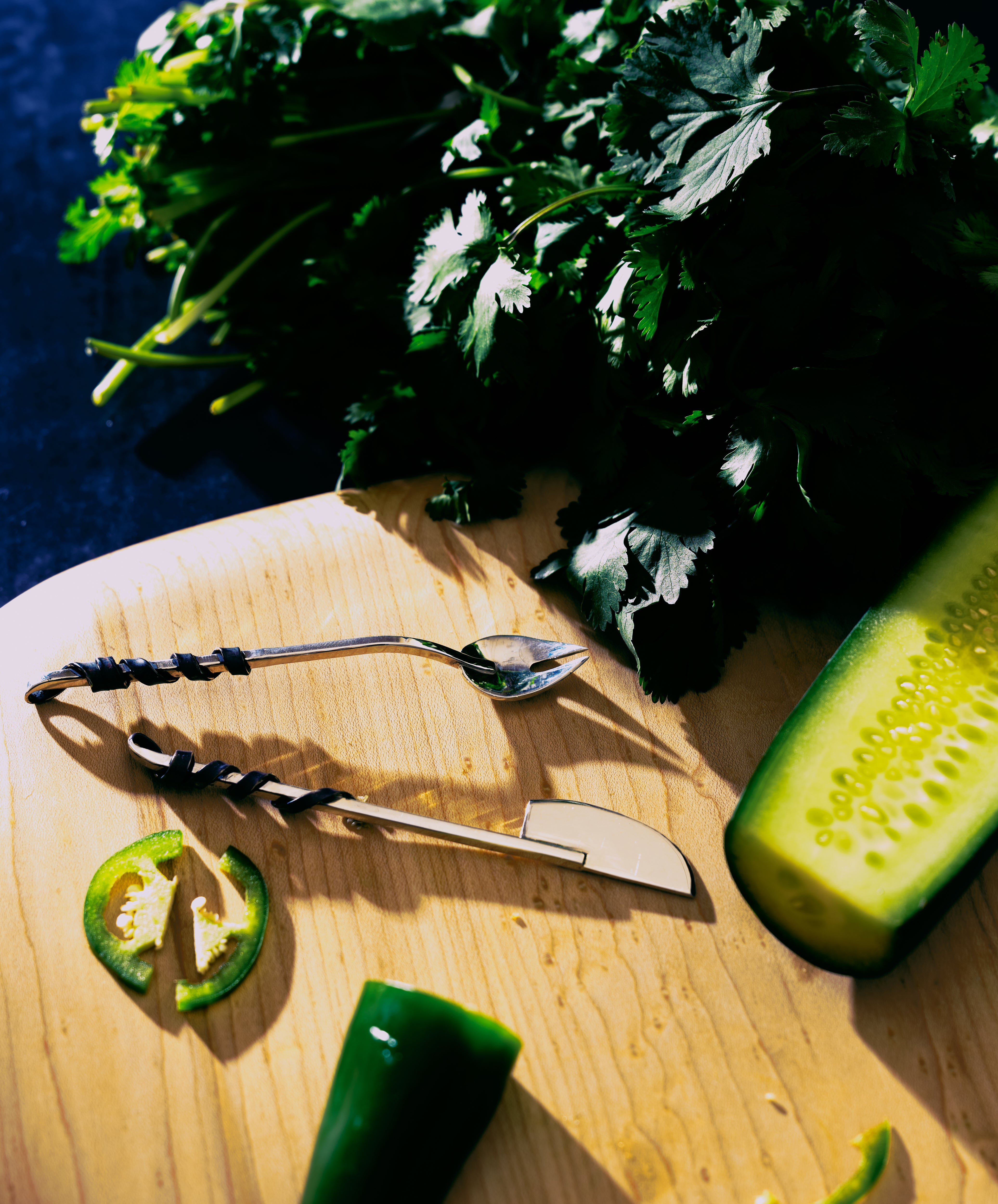 Silver aperitivo set in situ on cutting board with cilantro, cucumber, and jalapeño.