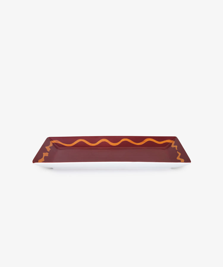 Hand Painted Double Serpent Tray. Rectangular porcelain tray in burgundy with ochre snake border, angled side view.