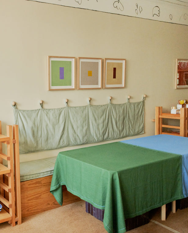 Room with two beds, green and blue covers, and three framed abstract artworks on the wall