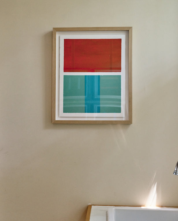 Framed abstract artwork with red and teal blocks hanging above a sink