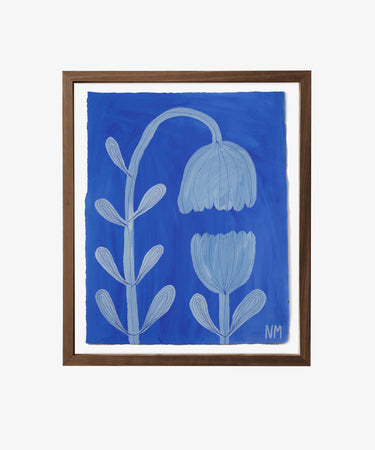 Flowers in Bloom is a framed botanical art piece depicting two stylized blue flowers with curved stems and leaves on a blue background, signed NM at the bottom right, and featured in the Art360 exhibition.