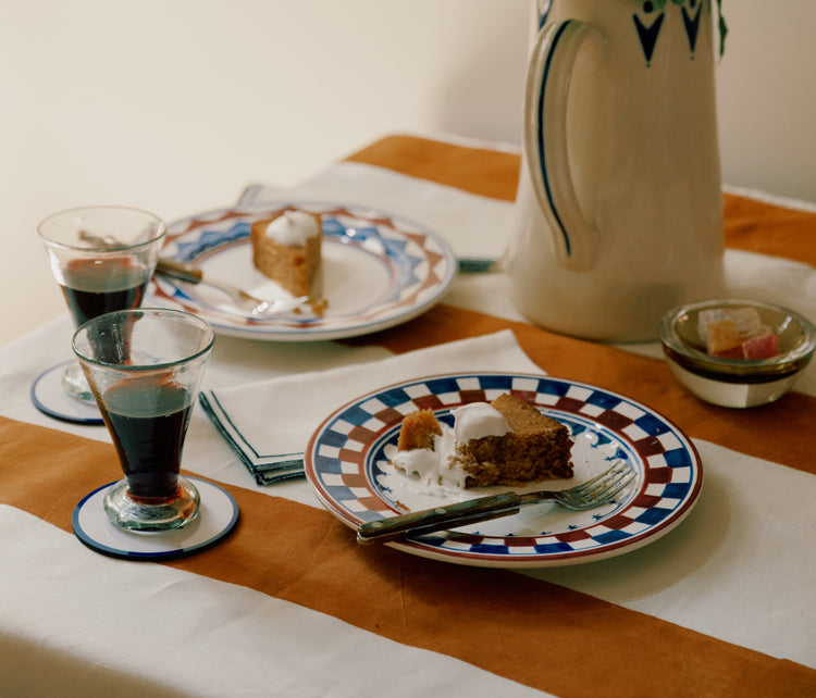 Table setting with dessert plates, coffee glasses, and a vase of flowers.