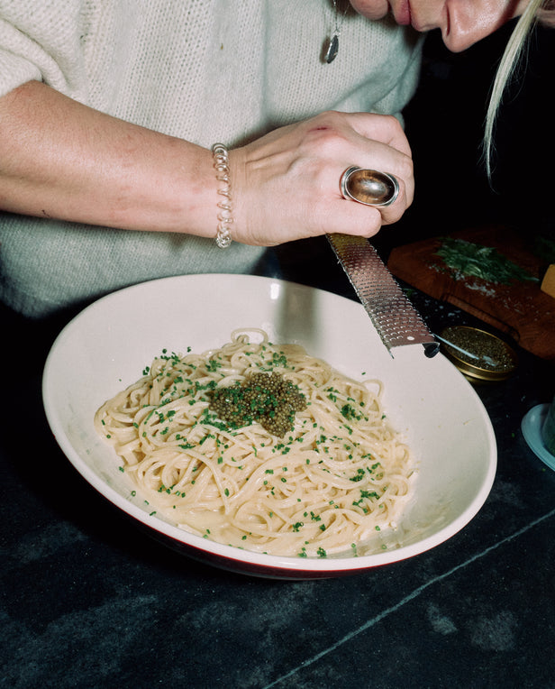 hand shaving cheese on pasta