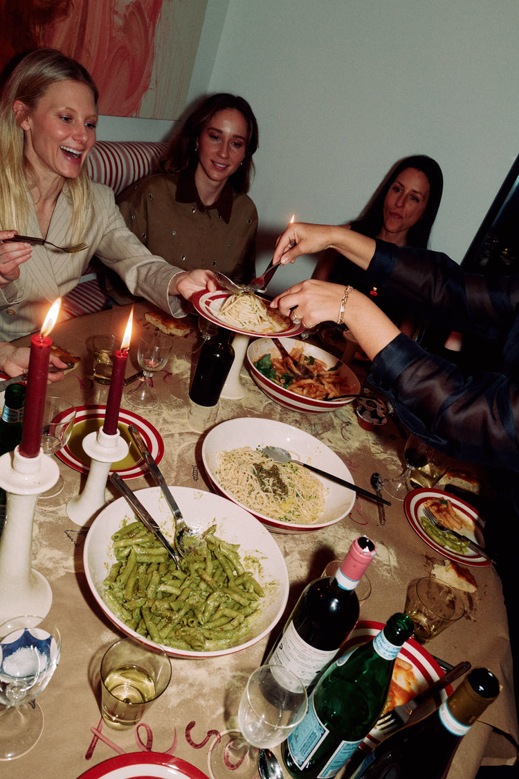 woman plating pasta at a table to other women