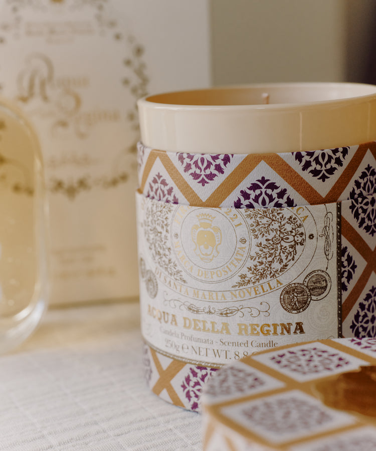 A close-up of the Acqua Della Regina Bundle, featuring a scented candle with a decorative label that highlights the iconic Florentine fragrance, displayed on a light surface.