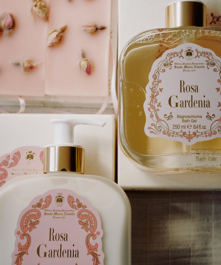 The Rosa Gardenia Bundle features bath gel, fluid cream with decorative labels, and a rosebud-topped pink soap, all filling the air with Rosa Gardenia and sandalwood scents.