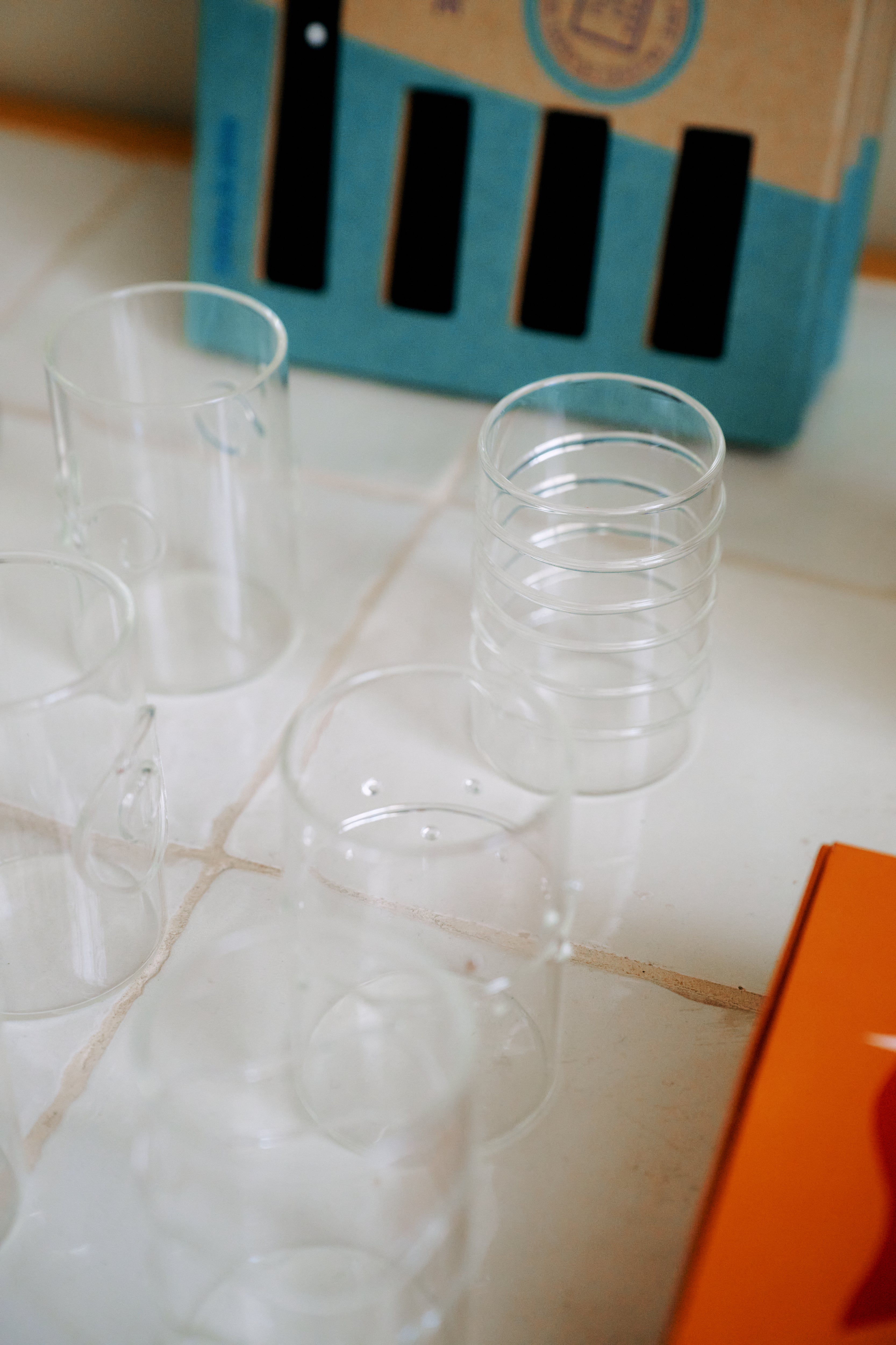A set of six Deco Shot Glasses is arranged on a tiled surface, with a cardboard box and an orange object partially visible in the background—perfect for serving limoncello or grappa.