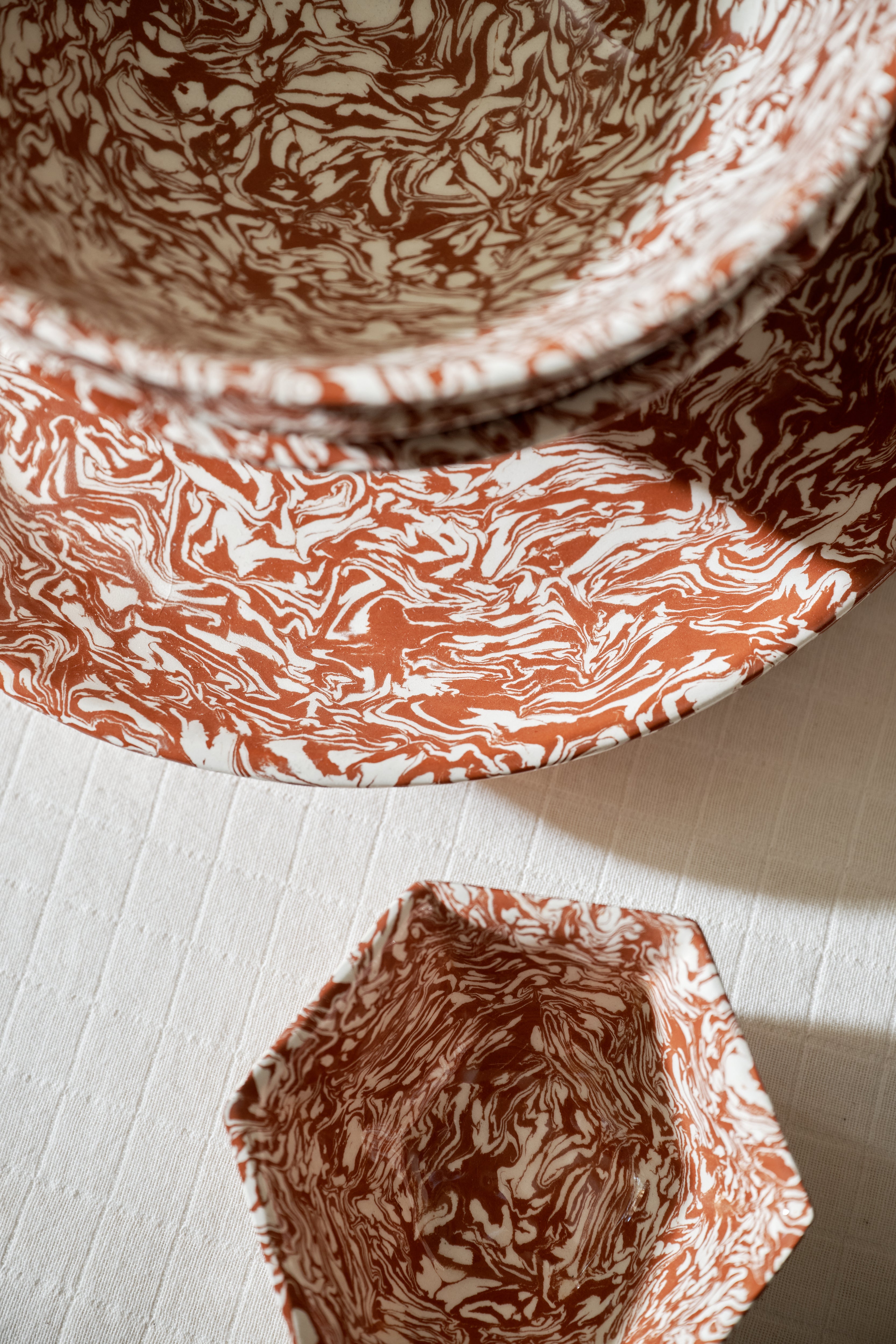 Three Celine Serving Platters, each handcrafted with red and white Aptware marbled patterns, are arranged on a textured white surface and viewed from above.