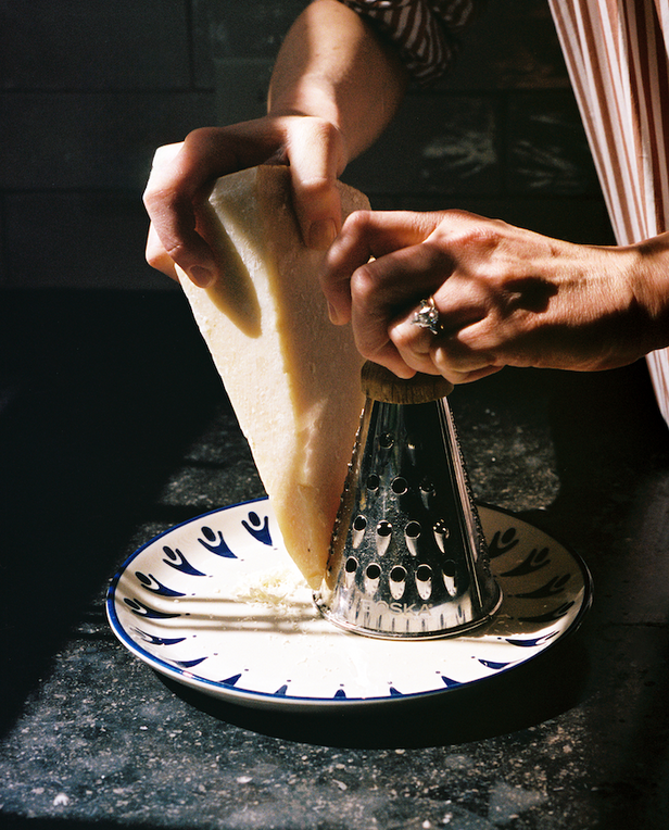 hand shaving parmesan onto plate
