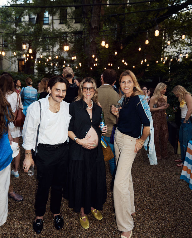 Group of people at an outdoor event with string lights and a casual atmosphere.