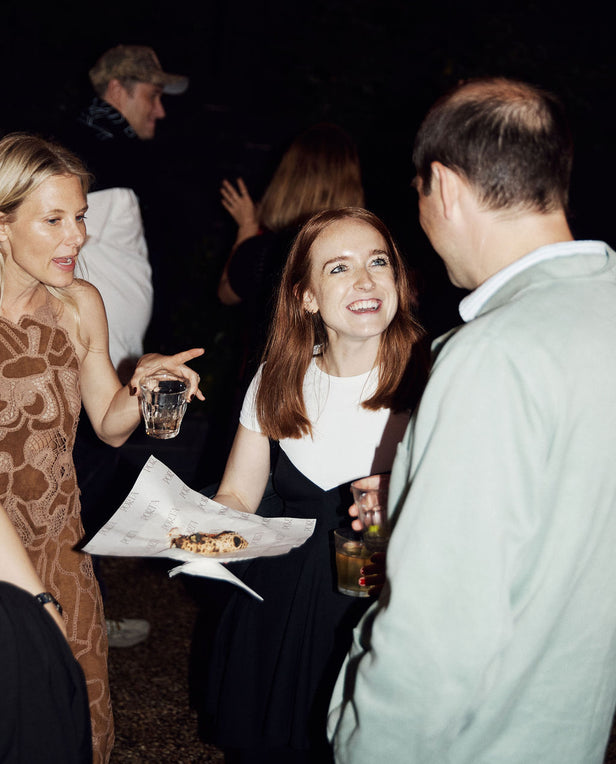 People socializing at a party with drinks and food.