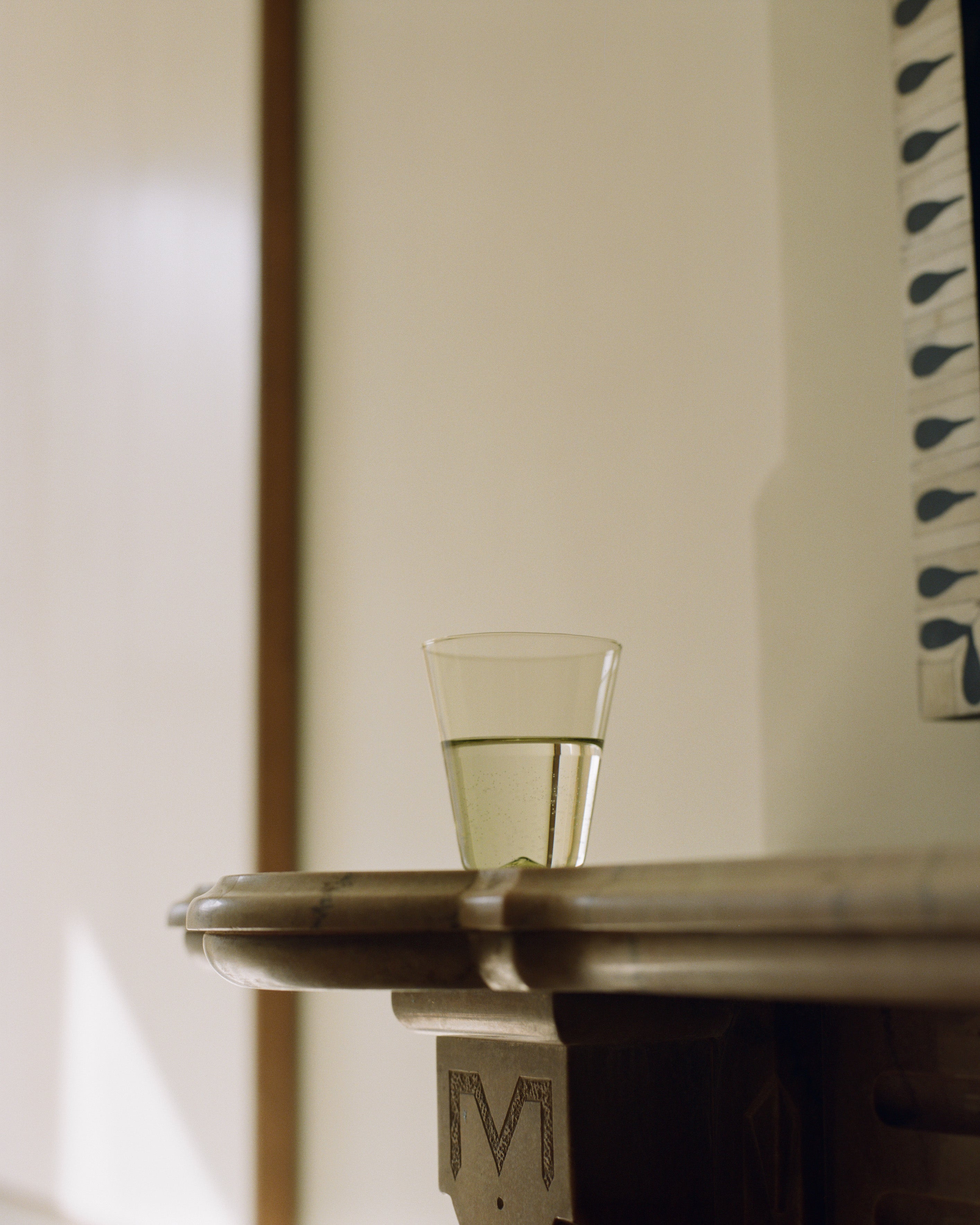 Marena Water Glass sitting on end of brown table.