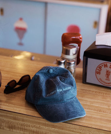 The Closed for August Cap—a blue European out-of-office hat embroidered with 
