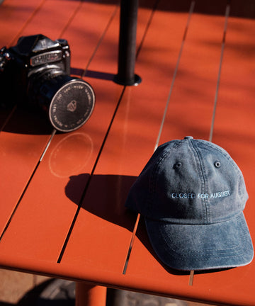 The Closed for August Cap—a blue cap with 