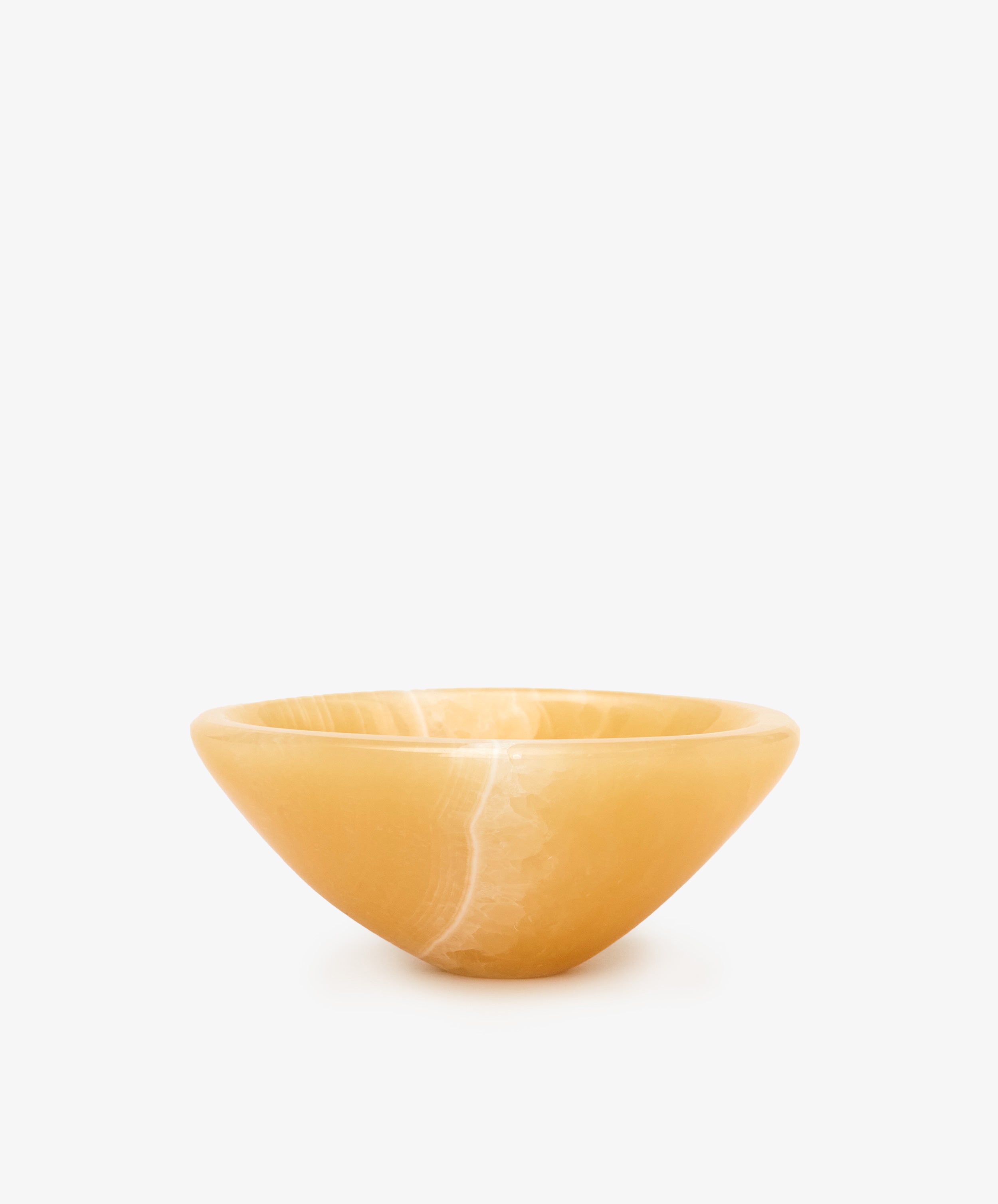 Handcrafted from polished yellow onyx with subtle veining, the Akila Catchall is a smooth, shallow bowl that adds refined decorative accents against a plain white background.