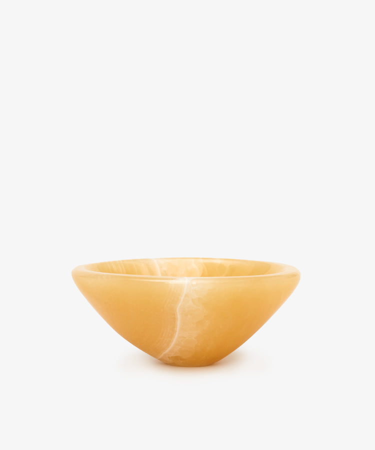 Handcrafted from polished yellow onyx with subtle veining, the Akila Catchall is a smooth, shallow bowl that adds refined decorative accents against a plain white background.