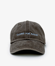 The Closed for August Cap is a brown baseball hat featuring light blue CLOSED FOR AUGUST embroidery on the front—perfect for channeling European summer vibes with easy style and sun protection.