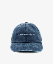 The Closed for August Cap is a blue denim baseball cap with white embroidered 