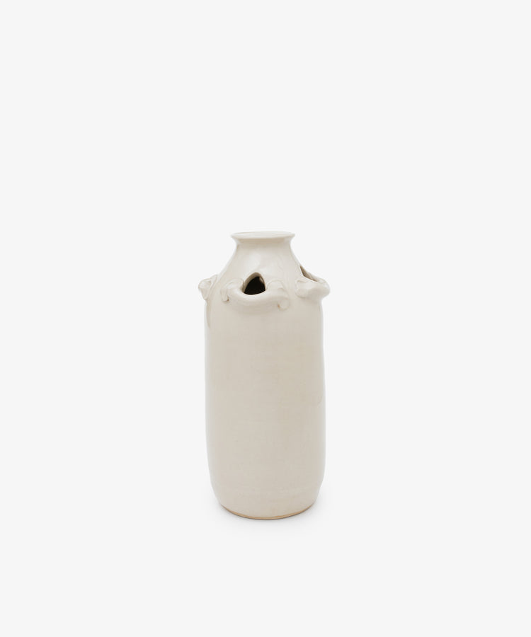 The Mini Candlehat Vase is a tall, cylindrical off-white ceramic piece with small looped handles and a narrow opening, inspired by 17th-century vessels, shown against a plain white background.
