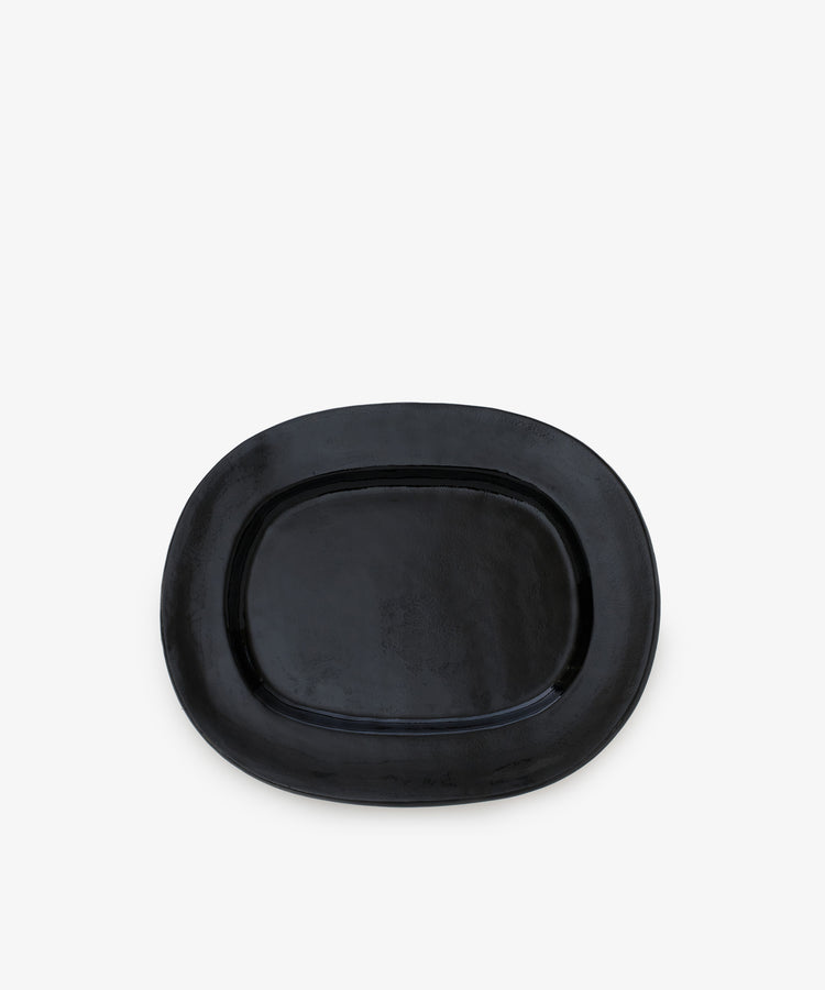 A small, black, rectangular ceramic serving platter with a glossy finish is displayed against a plain white background, adding a touch of modern tableware elegance.