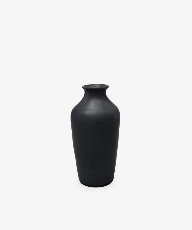 The Wheel Thrown Vase is a tall, matte black sculptural piece with a narrow neck and wide body, set against a plain white background.