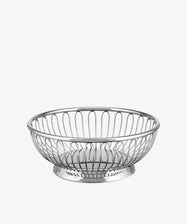 The Round Wire Basket is a silver, round Alessi basket with an open wire design and solid base, ideal for use as a stylish fruit or bread basket, shown against a plain white background.