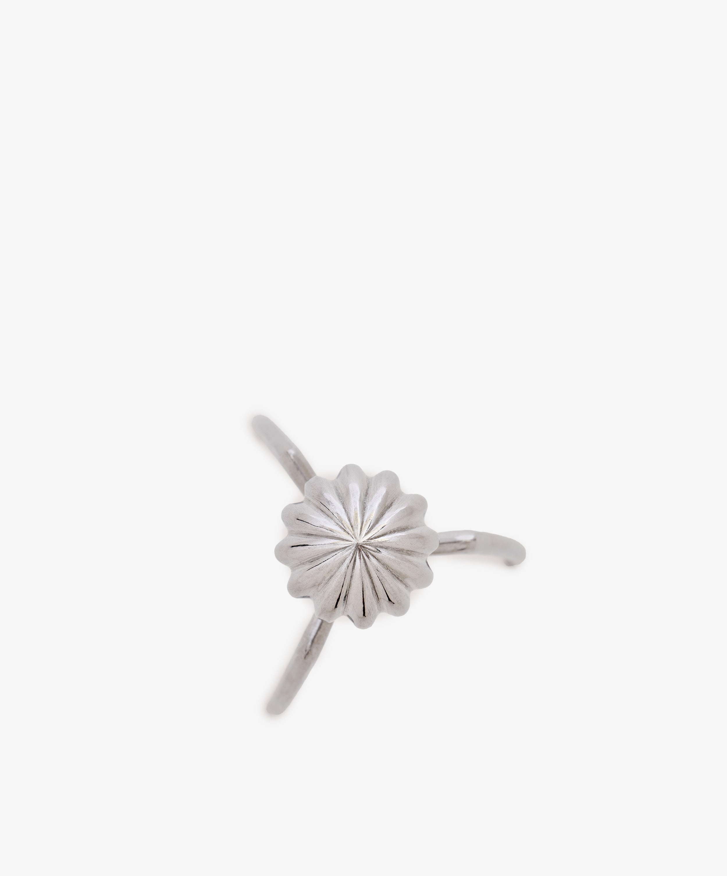 A silver ring inspired by the sculptural lines of the Juicy Salif Citrus Squeezer, featuring a central flower-shaped design with a ridged texture, set on a thin band against a white background.