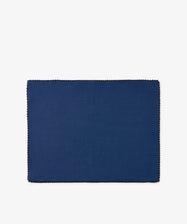 A set of six Nico Placemats, featuring a rectangular shape in indigo blue with stitched borders, is centered on a white background. These handmade placemats add a touch of elegance to any table setting.