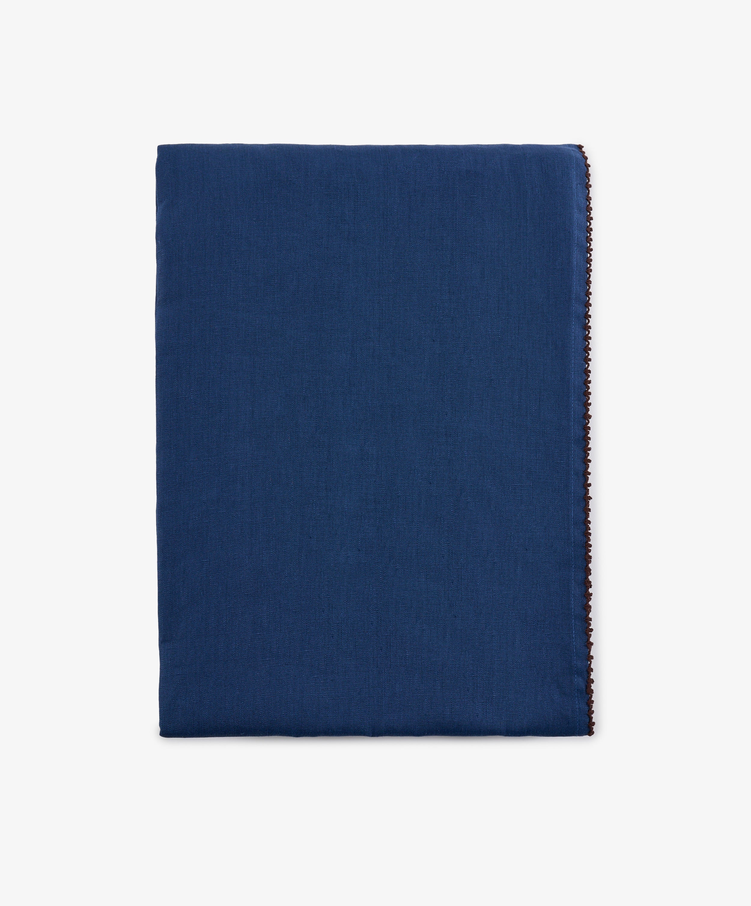 A neatly folded, rectangular Nico Tablecloth in indigo blue linen with a clean, simple appearance and hand-finished edges, displayed against a plain white background.