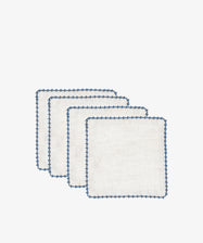 Set of four Nico Cocktail Napkins, each hand-finished in white with blue scalloped edges, displayed in a staggered stack on a plain white background.