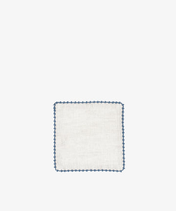 The Nico Cocktail Napkin, Set of 4, features white linen with a blue scalloped edge, hand-finished and showcased on a plain white background.