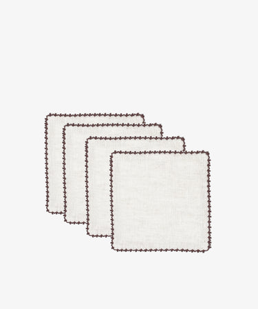 The Nico Cocktail Napkin, Set of 4, features white square napkins hand-finished with brown decorative edge stitching, showcasing the artisanal quality of Portuguese linens.