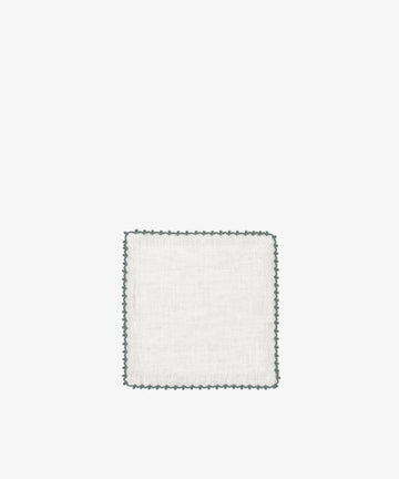 The Nico Cocktail Napkin, Set of 4 features square white linen napkins with a decorative dark scalloped edge, displayed on a plain white background.