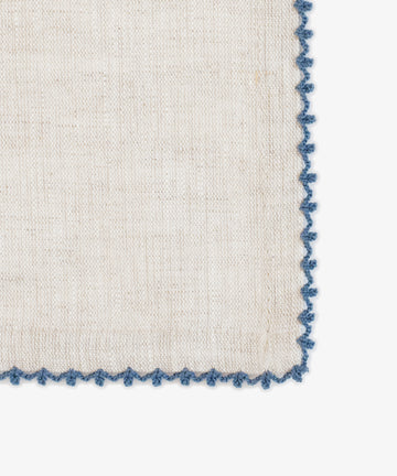 The Nico Napkin, Set of 6, features beige linen with a blue scalloped embroidered edge, resting elegantly against a white background to elevate any dining setting.