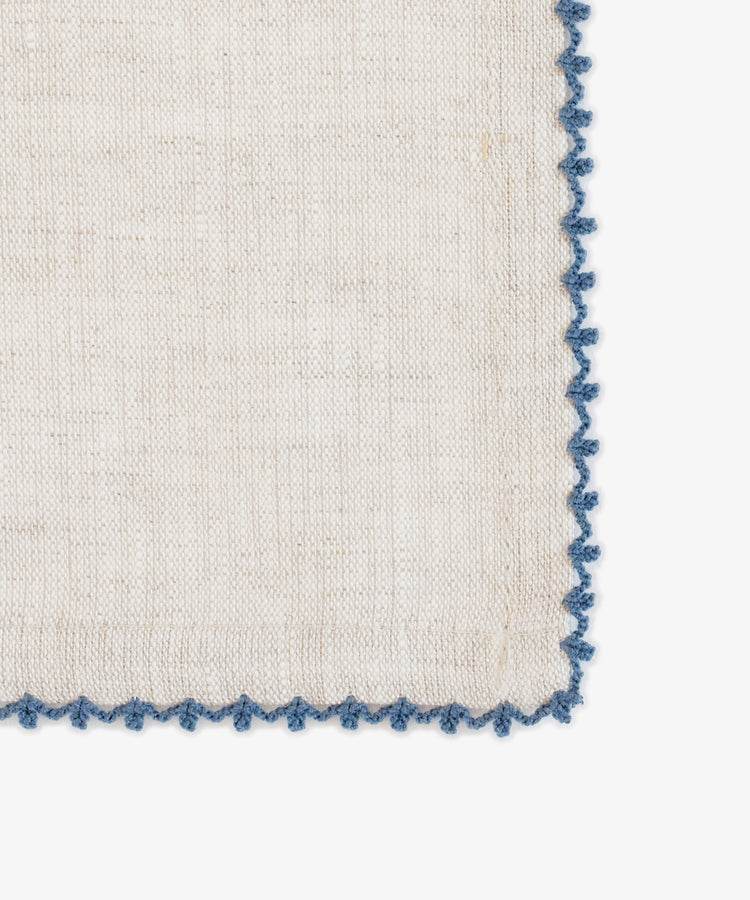 The Nico Napkin, Set of 6, features beige linen with a blue scalloped embroidered edge, resting elegantly against a white background to elevate any dining setting.