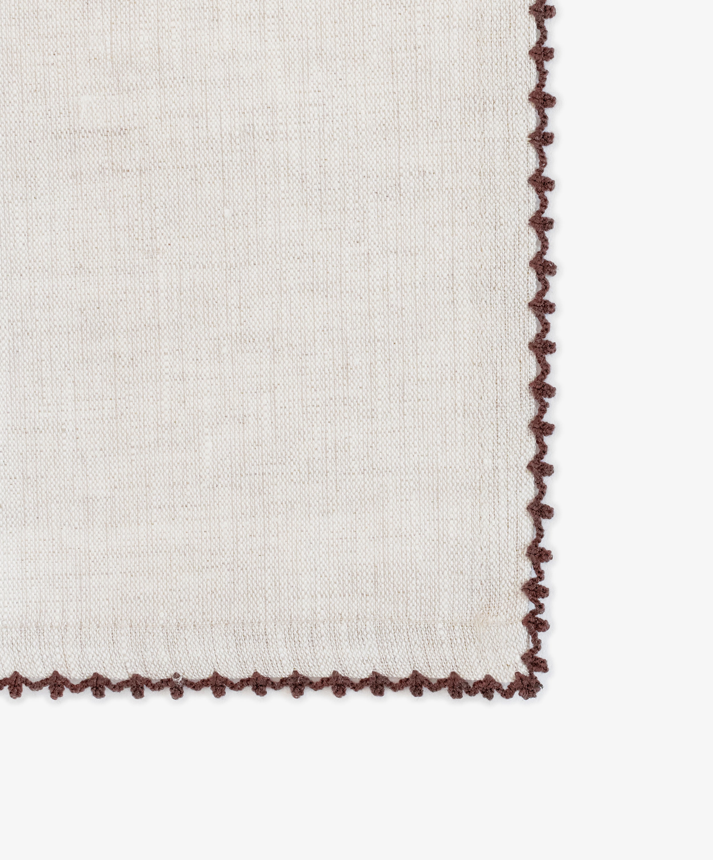 A close-up of the Nico Napkin, Set of 6, featuring beige fabric with brown crochet edging on a white background, highlights the elegance of modern table linens.