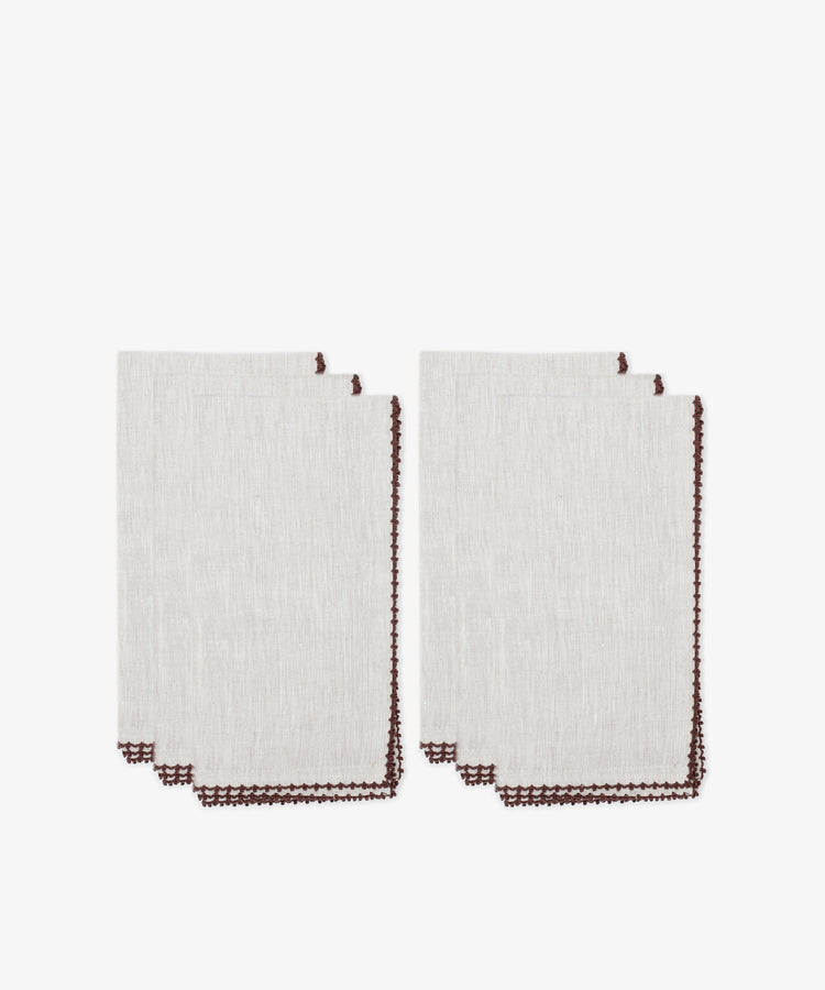 Six folded beige Nico Napkins with brown contrast stitching, arranged in two overlapping stacks on a white background—perfect modern table linens for any setting.