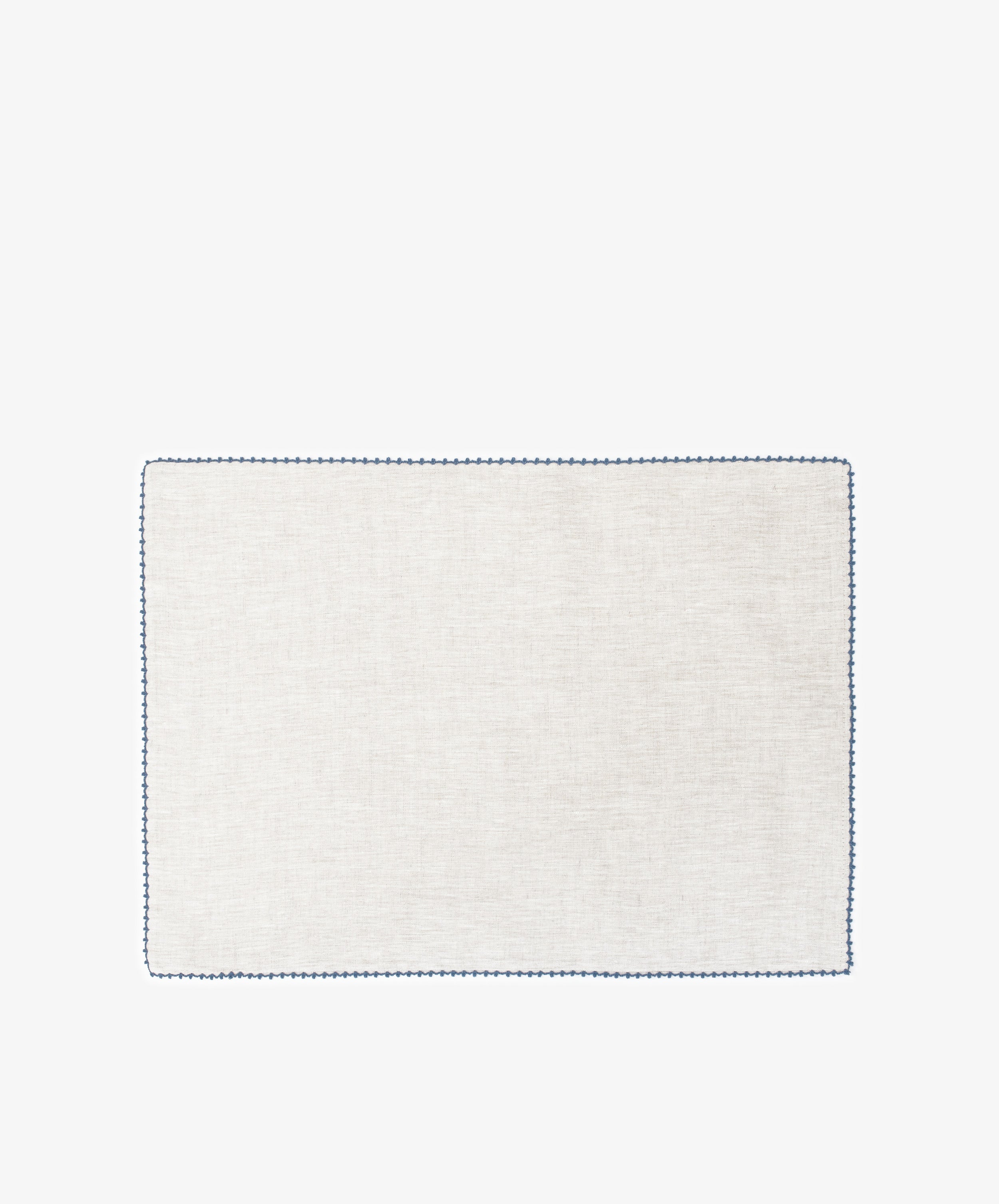 The Nico Placemat, Set of 6, features rectangular, light-colored linen with a simple blue hand-stitched edge—ideal for elegant table decor. Displayed on a white background.