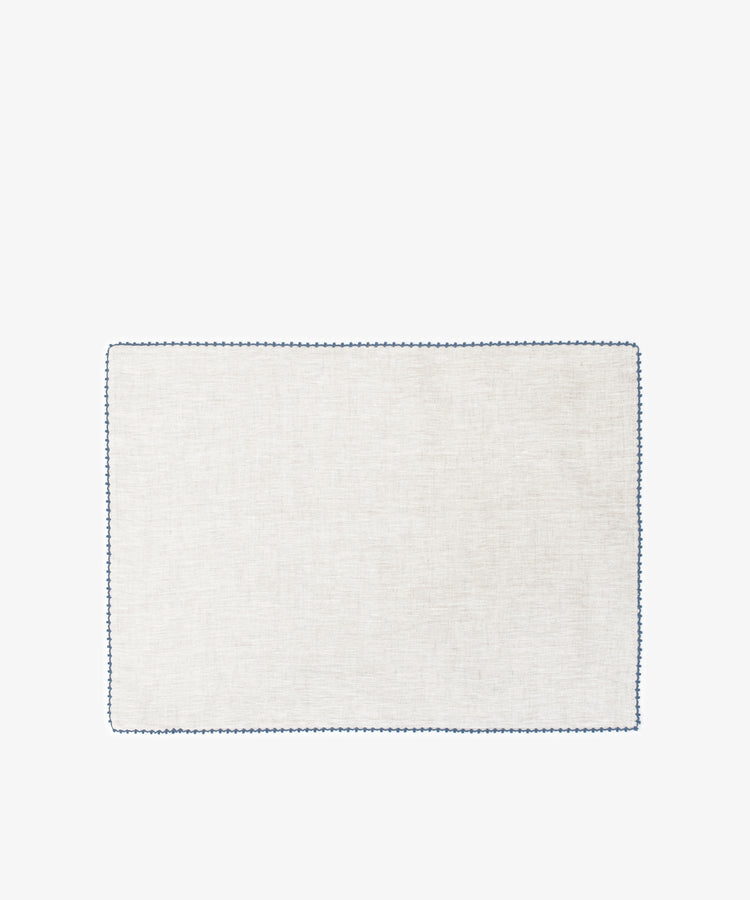 The Nico Placemat, Set of 6, features rectangular, light-colored linen with a simple blue hand-stitched edge—ideal for elegant table decor. Displayed on a white background.