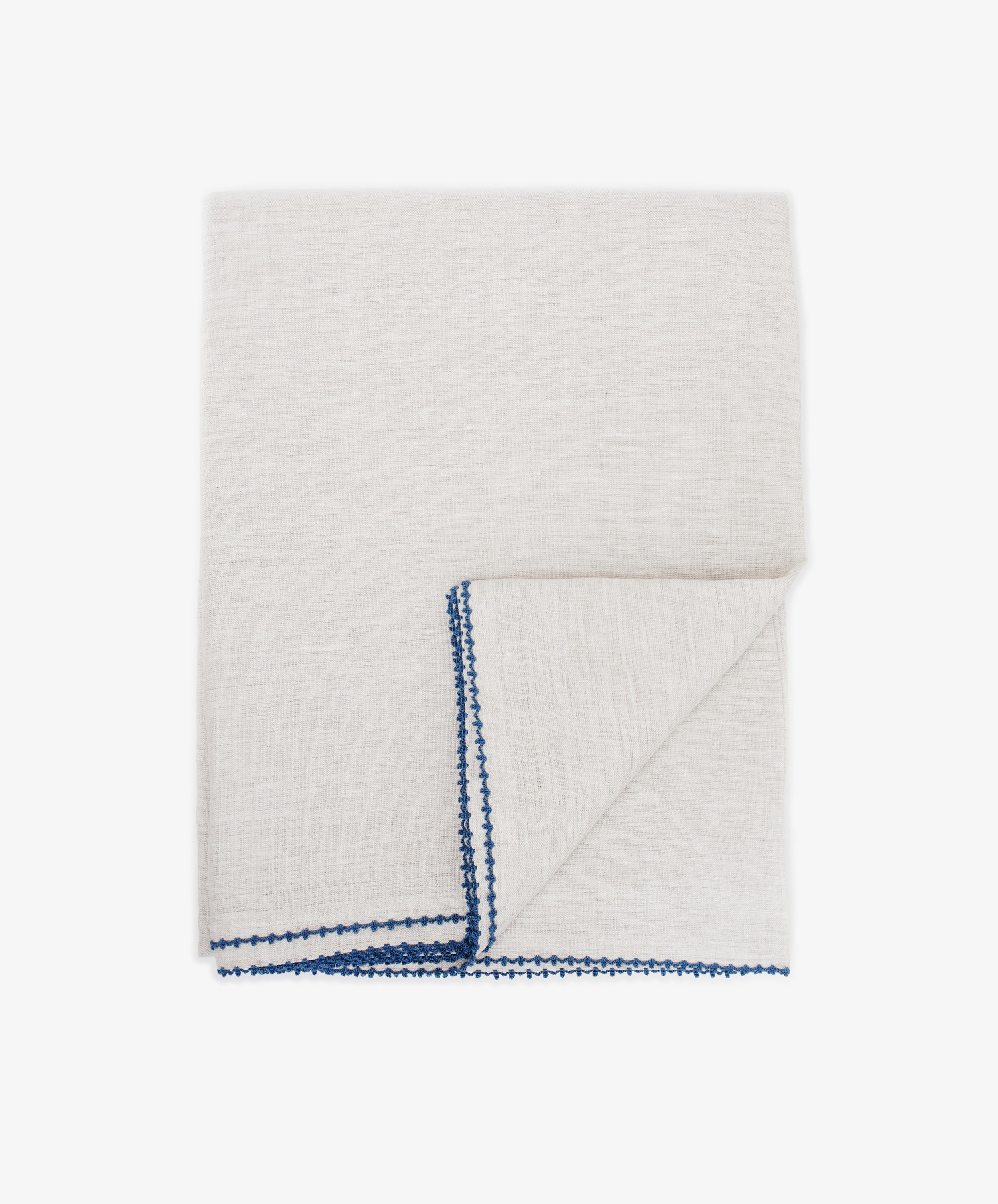 The Nico Tablecloth, in light gray with blue hand-stitched edging for elegance, is displayed folded on a white background.