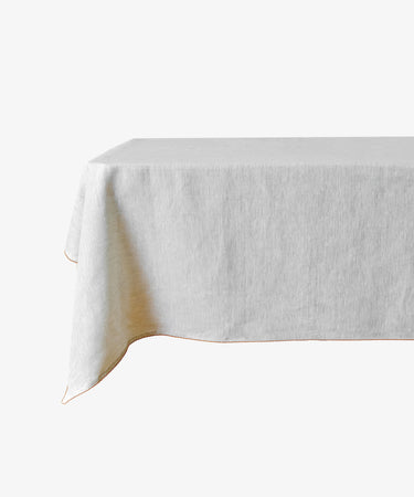 A rectangular table covered with the Nico Tableclothâ€”a plain, light-colored linenâ€”set against a white background.
