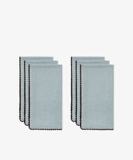 The Nico Napkin, Set of 6 in light blue linen are neatly folded and arranged in two separate stacks, each featuring a bold contrast stitch along the border.