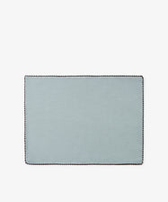 The Nico Placemat, Set of 6, features a rectangular design in light blue Portuguese linen with a dark scalloped border, thoughtfully crafted and displayed on a white background.