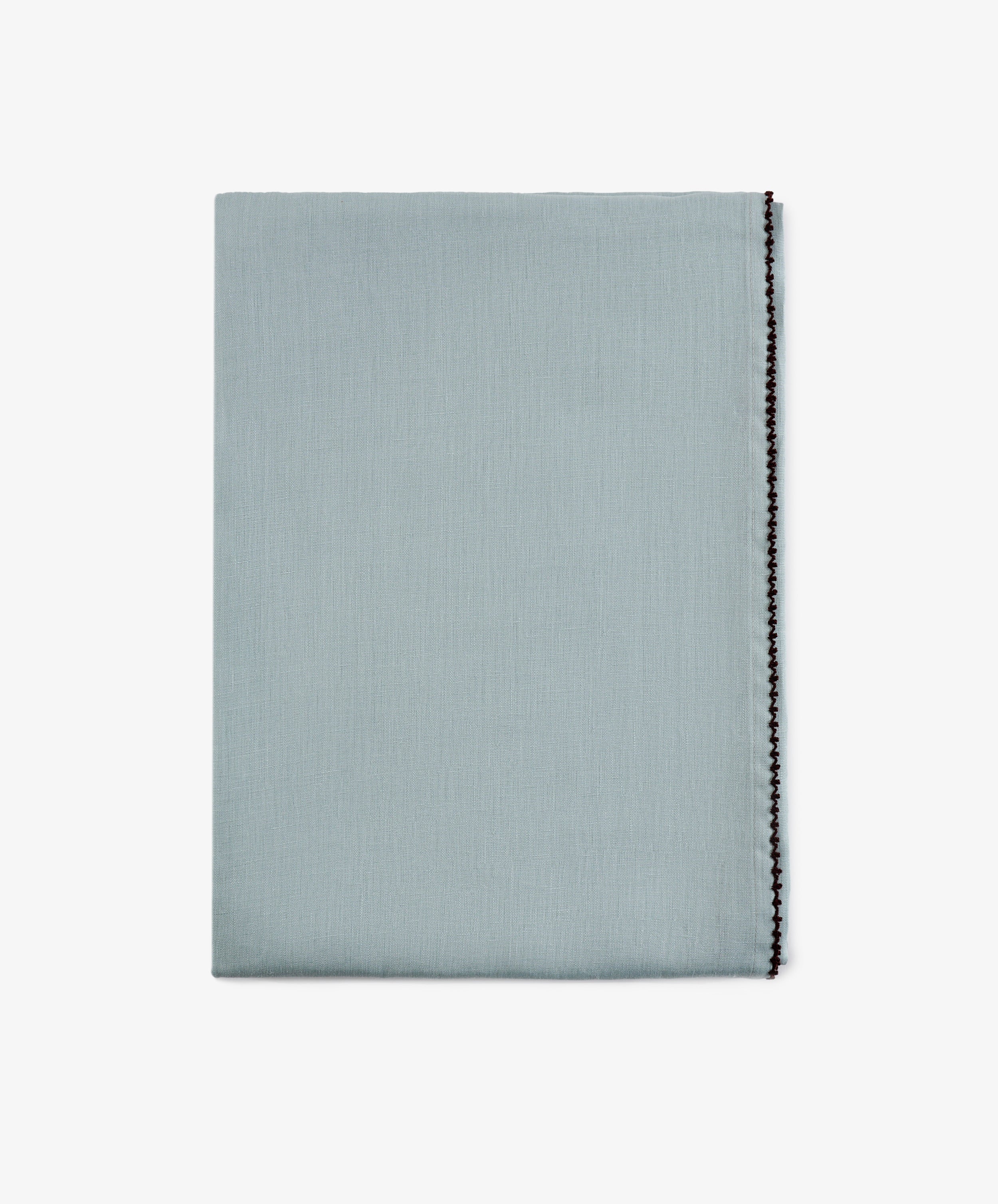 A neatly folded Nico Tablecloth in mint blue with a decorative black stitched edge, displayed against a plain white background. This elegant, hand-finished linen adds a refined touch to any setting.