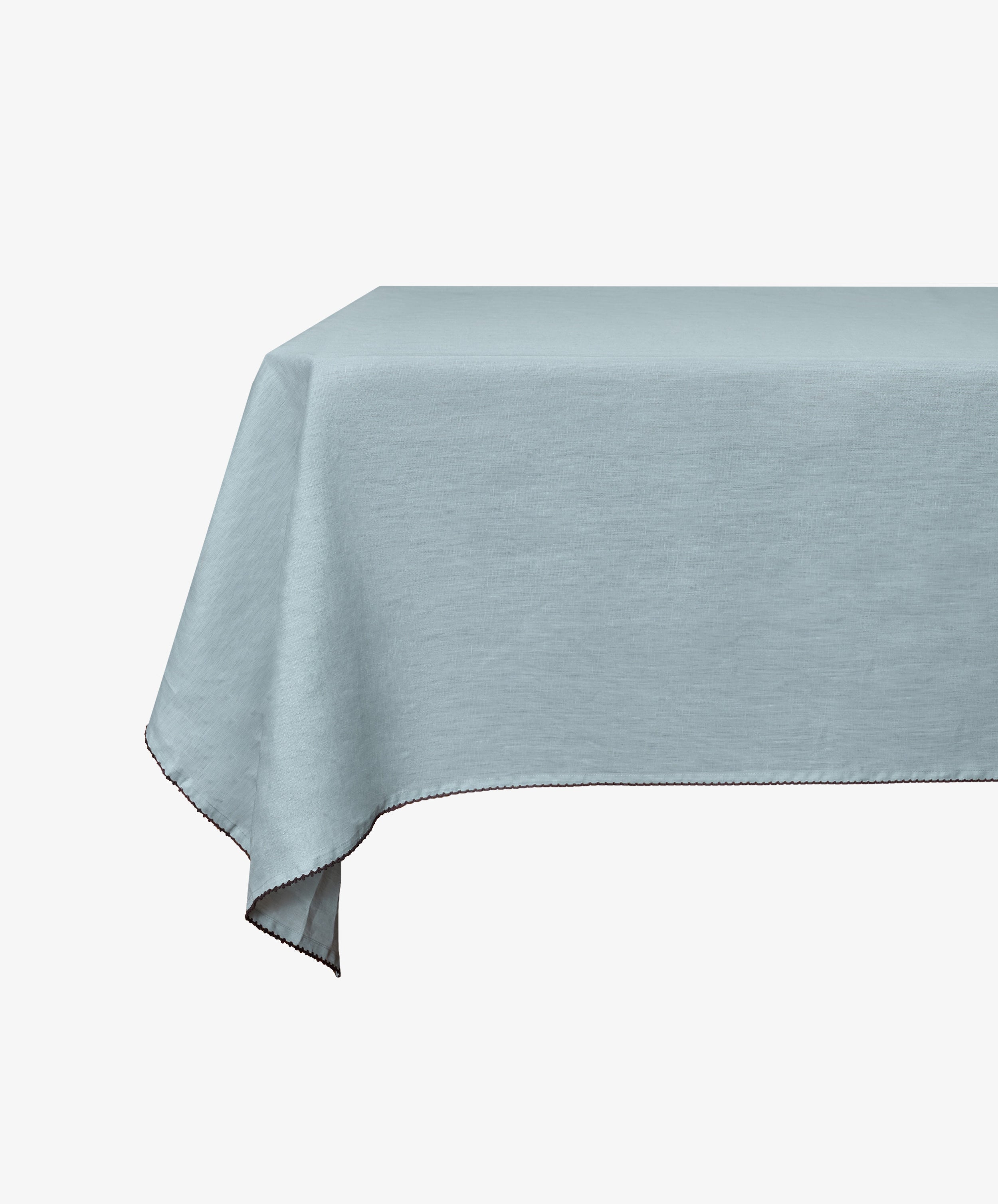 A rectangular table is adorned with the Nico Tablecloth—a mint blue, hand-finished linen piece—displayed against a plain white background.